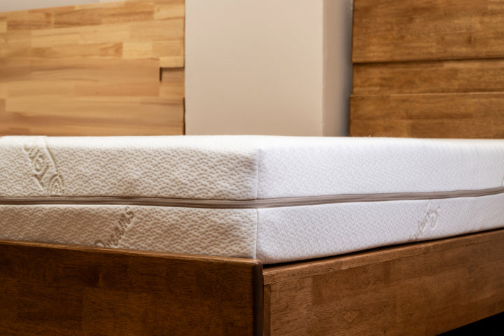 Close-up of a latex mattress on a wooden bed frame.